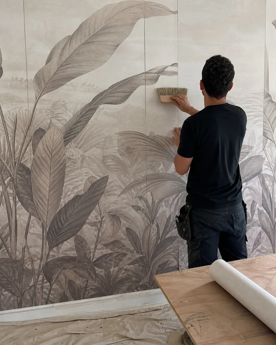 Installer smoothing a large botanical mural inside a clubhouse interior